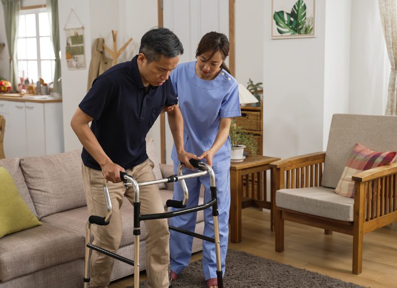 A therapist helping a patient walk with a frame